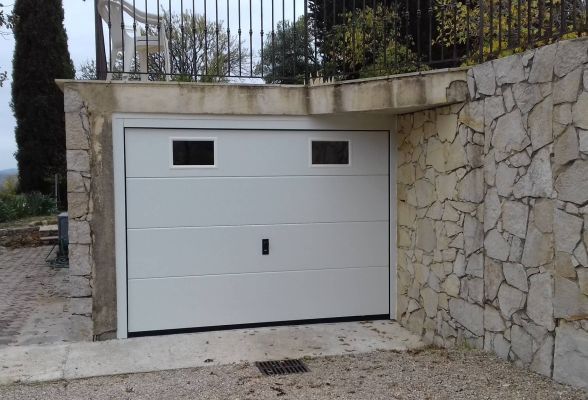 Porte de garage sectionnelle blanche avec hublots.