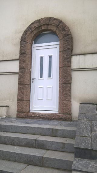 Porte d'entrée blanche cintrée en PVC.